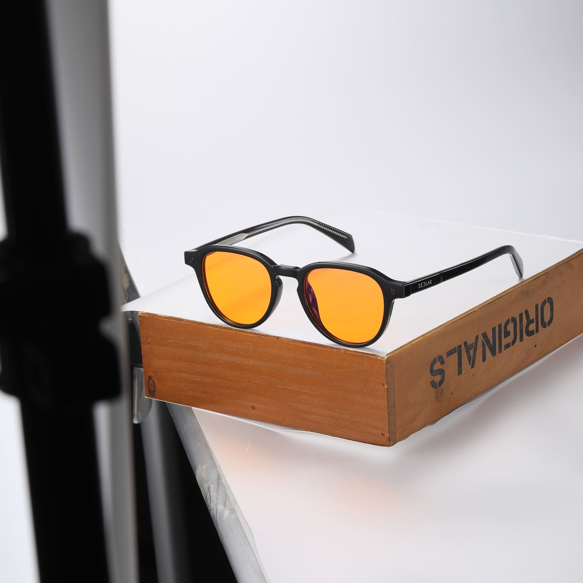 Black square-framed sunglasses with orange lenses on a white background.